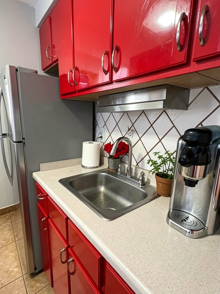 Bancada de granito com cooktop, armários brancos e coifa inox em cozinha integrada à sala.
